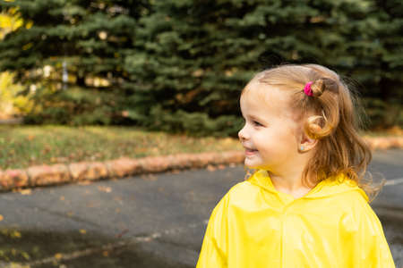 Cute blonde baby girl toddler wearing yellow stylish raincoat closeup. childhoodの写真素材