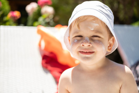 Sun protection. close up portrait of boy face with sunscreen, suntan lotion before tanning during a...