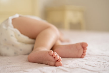 close up baby legs lying on bed at home