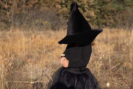 funny toddler girl in black witch hat with in natureの写真素材