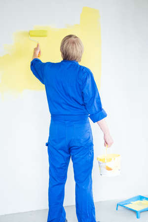 man painting wall in yellow color with roller. Renovation, repair and redecoration concept.の写真素材
