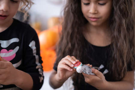 cute girl in witch costume witch having fun in kitchen, playing with skeleton, celebrating Halloween.の写真素材