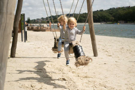 two child boys twins brothers playing on kids playground in a sunny autumn day.の写真素材