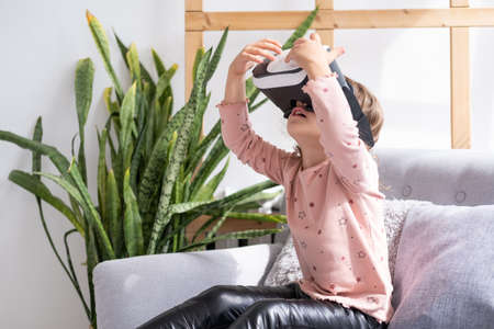 Cute little girl in virtual reality glasses at home. happy kid using VR headset.の写真素材