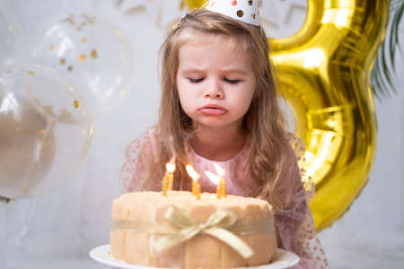 cute little child girl blowing candles on birthday cake and celebrating birthdayの写真素材