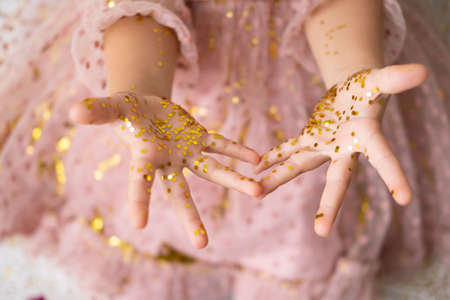 close up of child hands in confetti. kid in pink dress celebrating birthdayの写真素材