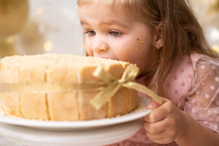 cute little child girl eating birthday cake without hand and celebrating birthday