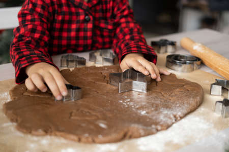 little kid girl in red pajama cooking festive gingerbread in christmas decorated kitchen. christmas cookiesの写真素材
