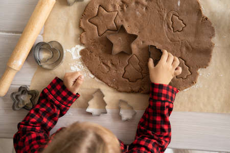little kid girl in red pajama cooking festive gingerbread in christmas decorated kitchen. christmas cookiesの写真素材