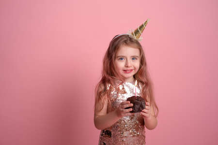 Funny child girl in sequins dress with birthday cupcake with candle on white background