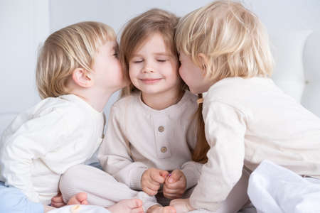 two cute kids blonde boys twins kissing little girl with long hair