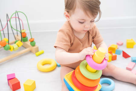 cute baby girl playing with pyramid and wooden toys at home. early children developmentの写真素材