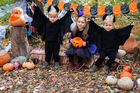 happy kids in halloween costumes having fun in halloween decorations outdoorの写真素材