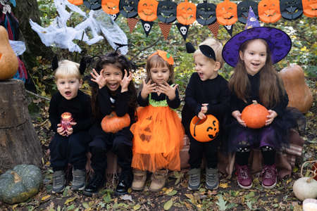 happy kids in halloween costumes having fun in halloween decorations outdoorの写真素材