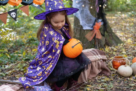 Halloween. cute little girl in witch costume with jack o lantern having fun outdoor