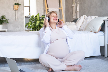 pregnant woman with big belly advanced pregnancy in wireless headphone listening musicの写真素材