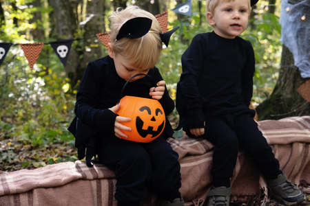 two happy twins boys kids in halloween costumes having fun in halloween decorations outdoor
