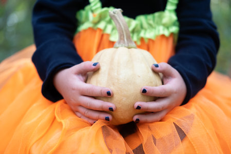 Halloween. close up girl holds pumpkin, having fun, celebrating Halloweenの写真素材