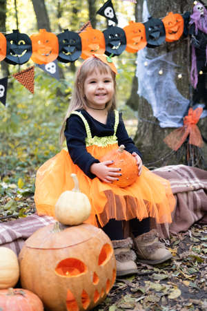 Halloween. cute girl in pumpkin costume with pumpkin outdoor, having fun, celebrating Halloweenの写真素材