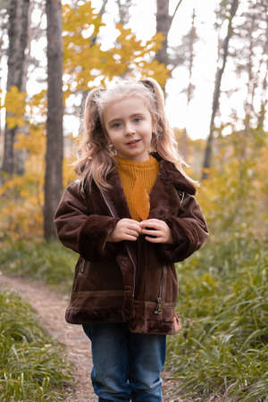 Happy little child girl smiling, holding autumn leaves, having fun in the fall forestの写真素材