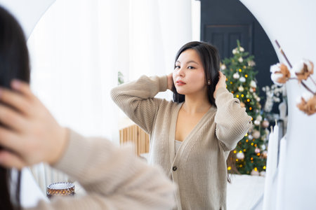 Young beautiful asian woman looking at her reflection in the mirror and smiling.の写真素材