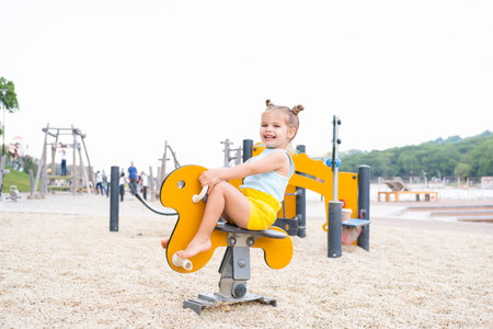 cute little child girl in colorful clothes playing on kids playground in summer day.の写真素材