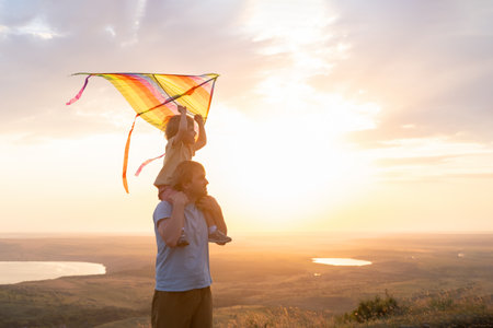 Happy man and little boy, father and sons, with kite in nature at sunset.の写真素材