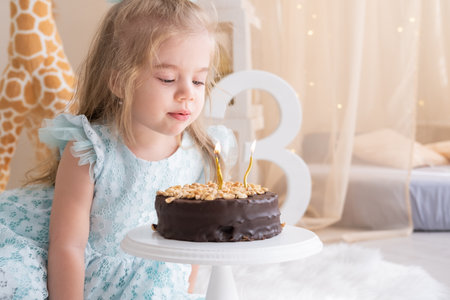 cute little child girl blowing candles on birthday cake and celebrating birthdayの写真素材