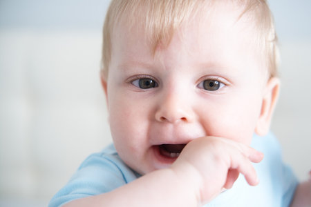 close up child with his fingers in his mouth, his teeth are teething. Baby teeth grow.の写真素材
