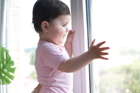 A toddler stays near the windowの写真素材