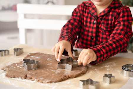 little kid girl in red pajama cooking festive gingerbread in christmas decorated kitchen. christmas cookiesの写真素材