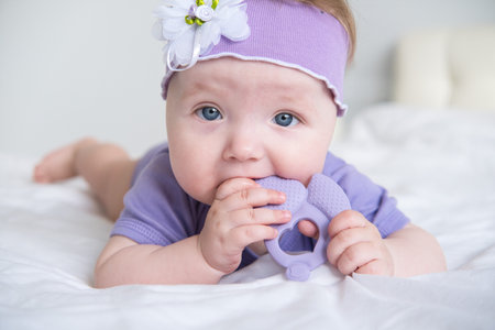 baby is gnawing on a violet teether. first teethの写真素材