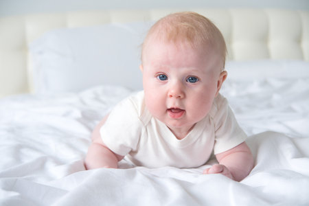 cute smiling baby lying on tummy on parent bedの写真素材