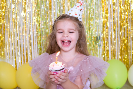 cute little child girl blowing candle on birthday cupcake and celebrating birthday.