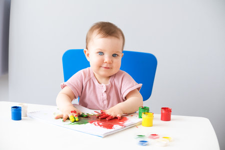child is drawing on white sheets with finger paintsの写真素材
