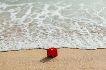 present gift in red box  on the beach in tropics. Present red box flowing in the sea. christmas holideys on the beachの写真素材