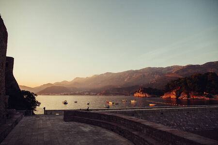 Sunset bay with boats and mountains in vintage colours film lookの写真素材