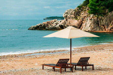 Luxury beach resort with two sunbeds and umbrella with nobody and mountain view in Milocer, Montenegroの写真素材