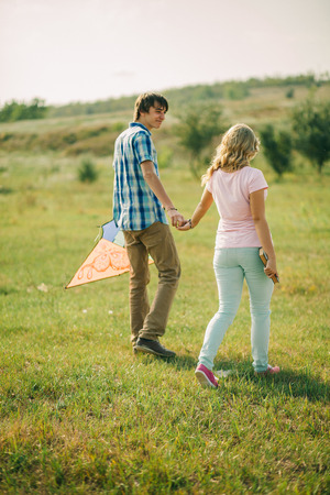 happy teenage love story couple in the field with kiteの写真素材