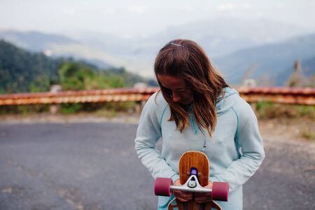 portrait of hipster girl dreaming  with longboard in the mountainsの写真素材