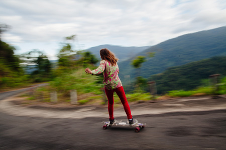 hipster girl longboarding high speed action in mountains