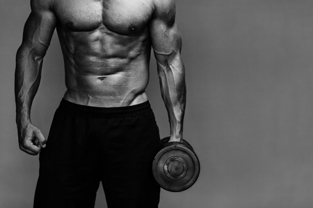 Close up of muscular bodybuilder guy doing exercises with weights over grey background. Black and whiteの写真素材