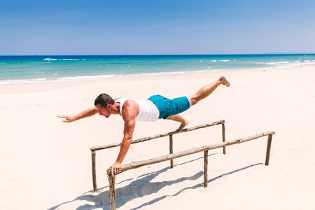 fitness man doing excercises on the beach with sea viewの写真素材