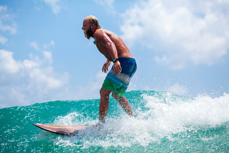 man with beard surfing wave splash activelyの写真素材