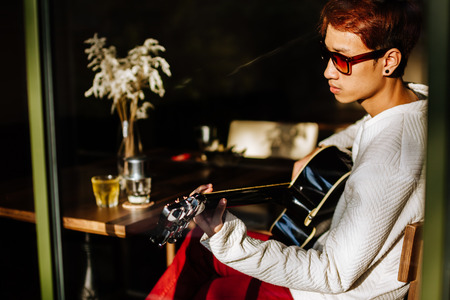 asian handsome guitar man play acoustic guitar in cafeの写真素材