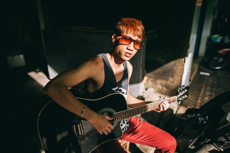 asian guitarist artist fashion man play guitar on streetの写真素材