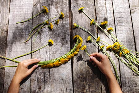 wreath of dandelions flowers handmade handicraft with flowers on vintage wood tableの写真素材