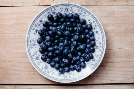 fresh juicy blueberry on plate and wood table top view