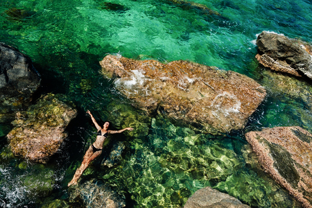 teenage girl swimming and relaxing in the sea blue lagoon aerial top viewの写真素材
