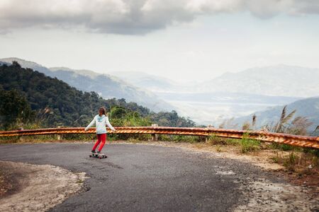 girl skateboarding in tropical mountainsの写真素材